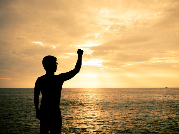 Человек в силуэте показывает свою руку на пляже Сансет
 - Фото, изображение