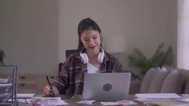 Young Asian Women Graphic designer Artist work on computer laptop and with graphic interactive drawing pen sitting in front of window at desk in office. High quality 4k footage - Imágenes, Vídeo