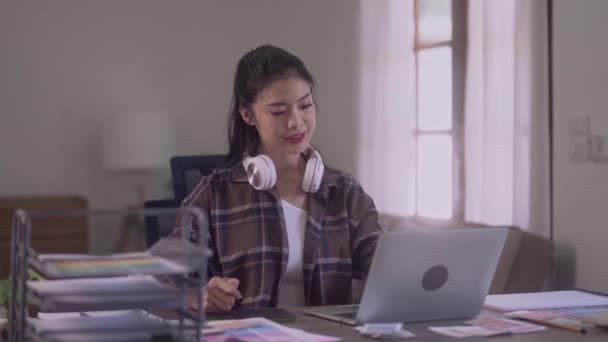 Young Asian Women Graphic Designer relaxing with stretching raised arms while taking break from work at her desk in creative office. High quality 4k footage - Séquence, vidéo