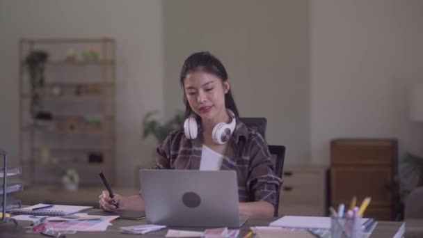 Young Asian Women Graphic Designer relaxing with stretching raised arms while taking break from work at her desk in creative office. High quality 4k footage - Séquence, vidéo