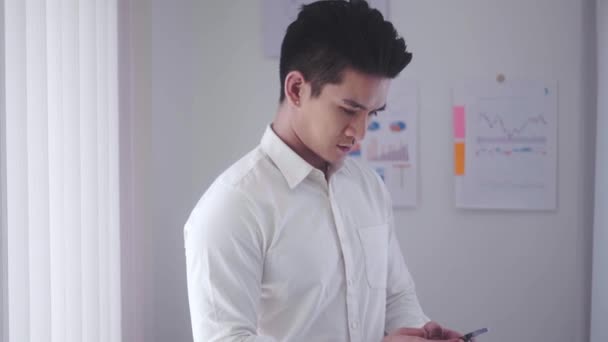 Asian businessman holding smartphone for chat online mobile applications sitting in office, Inspiring productivity with a wealth of technology. High quality 4k footage - Séquence, vidéo