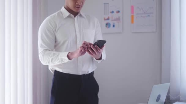 Asian businessman holding smartphone for chat online mobile applications sitting in office, Inspiring productivity with a wealth of technology. High quality 4k footage - Felvétel, videó
