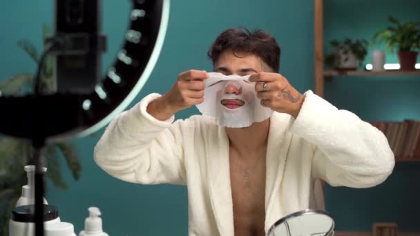 Blogování péče o pleť a koncepce krásy. Arabský mladý muž nahrává video tutorial doma aplikuje beauty sheet masku natáčí živé video na sociálních sítích. Kopírovat prostor - Záběry, video