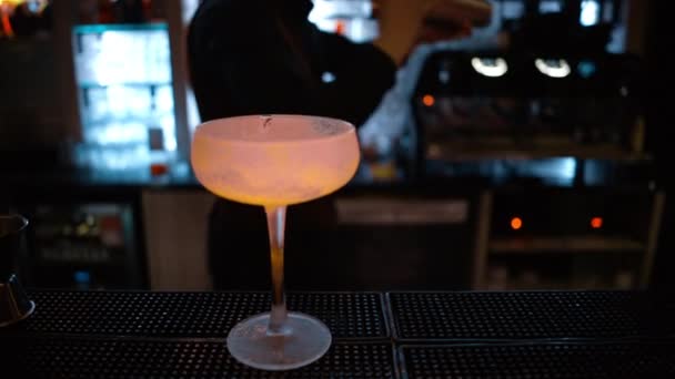 Бармен наливает зеленый алкогольный коктейль в бар с неоновыми огнями ночью - Кадры, видео
