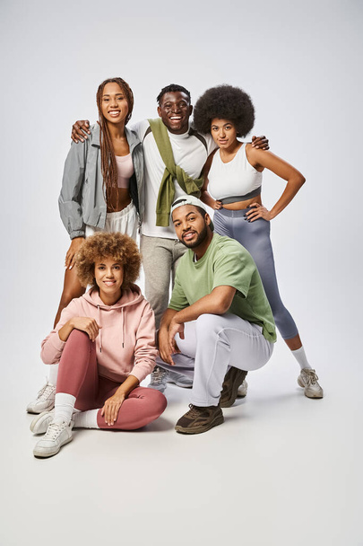 vrolijke Afrikaans-Amerikaanse mensen in sportkleding staan samen op grijze achtergrond, Juneteenth - Foto, afbeelding