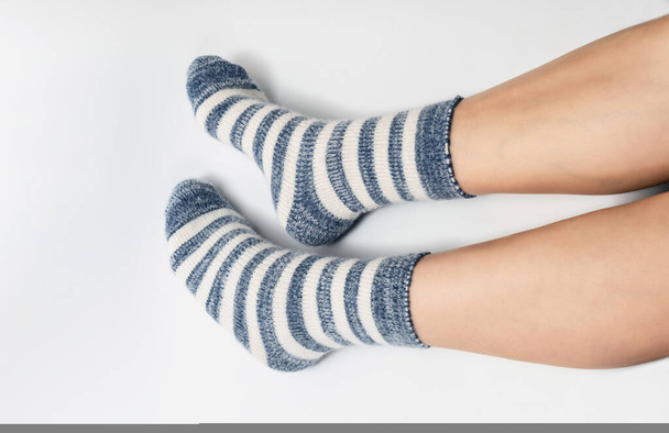 Вид збоку на ноги в шкарпетках двох кольорів, чергуючи синій і білий. Білий фон, ізольований - Фото, зображення