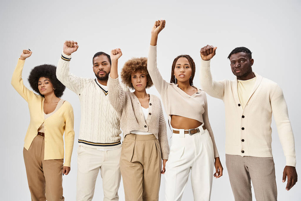 Juneteenth és aktivizmus, boldog afro-amerikai emberek összeszorított ököllel szürke háttér - Fotó, kép