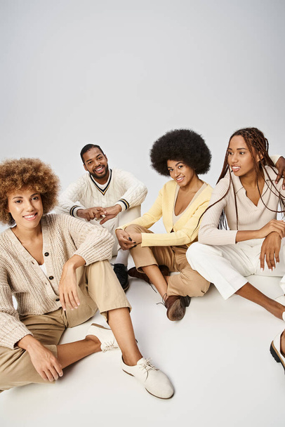 groep van vrolijke Afrikaanse Amerikaanse vrienden in casual kleding zitten op grijze achtergrond, Juneteenth - Foto, afbeelding