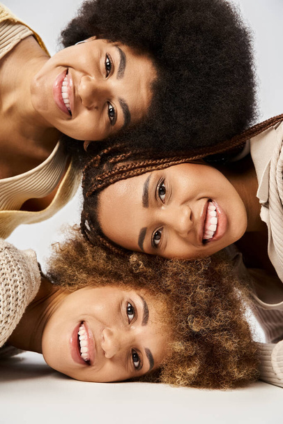drie gelukkig Afrikaans Amerikaanse vrienden staan in elegante kleding op grijze achtergrond, Juneteenth - Foto, afbeelding