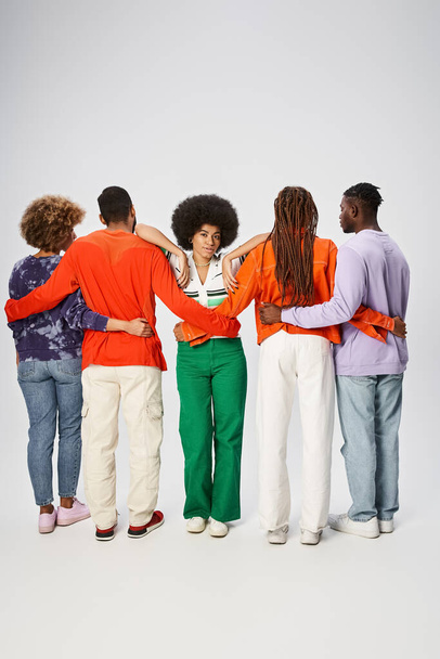 кудрявая африканская американка, опирающаяся на друзей, обнимающихся на сером фоне, концепция июня - Фото, изображение