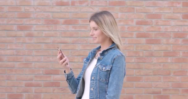 Esta sequência apresenta uma jovem mulher em uma jaqueta de ganga na moda, totalmente envolvida com seu smartphone em uma rua da cidade, com uma parede de tijolo rústico como pano de fundo. A filmagem capta sua mudança de - Filmagem, Vídeo