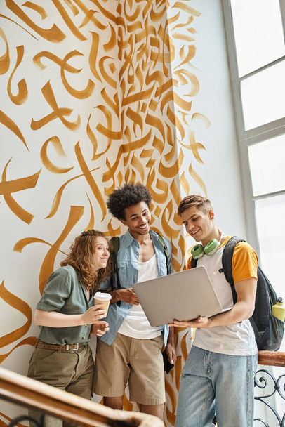 взволнованные мультикультурных студентов, глядя на ноутбук на лестнице общежития, дружбы и путешествий - Фото, изображение