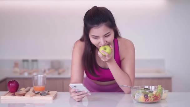 スポーツウェアでリンゴを食べ,スマートフォン,スポーツ,テクノロジーのコンセプトを使用するスポーツの若いアジアの女性. ライフスタイルと医療。 高品質の4k映像 - 映像、動画