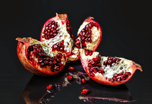 Sliced whole red pomegranate on shiny background. Reflections of pomegranate fruits - Фото, изображение