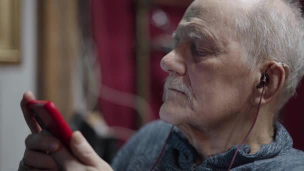 Starší muž sedí na vozíku rolování na sociálních sítích na smartphonu - Záběry, video