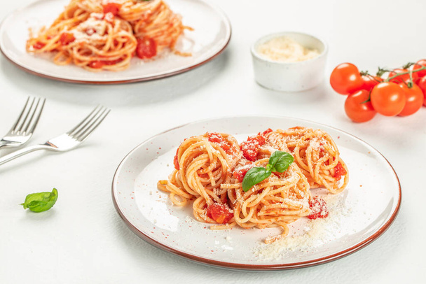 Italiaanse spaghetti pasta met tomatensaus, kaas parmezaanse kaas en basilicum op witte achtergrond, bovenaanzicht. - Foto, afbeelding
