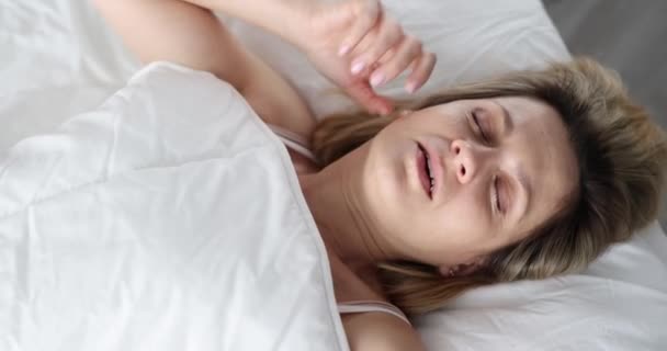 Женщина просыпается с криком, лежа на кровати и глядя под одеялом. Ночные страсти и концепция плохих снов - Кадры, видео