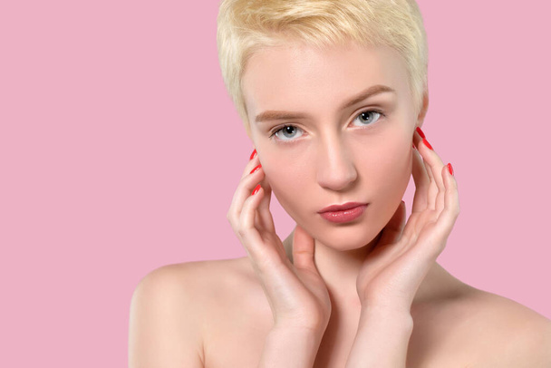 Portret van een mooie vrouw met kort blond haar, mooie frisse make-up en een gezonde schone huid op een roze achtergrond. Concept voor make-up en cosmetologie. - Foto, afbeelding