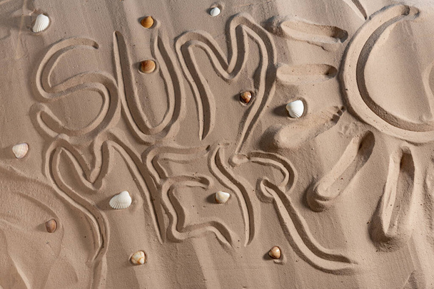 Fondo de arena de playa. Textura de arena con conchas marinas e inscripción verano, concepto de vacaciones, fondo abstracto para el diseño, Vista superior. - Foto, Imagen