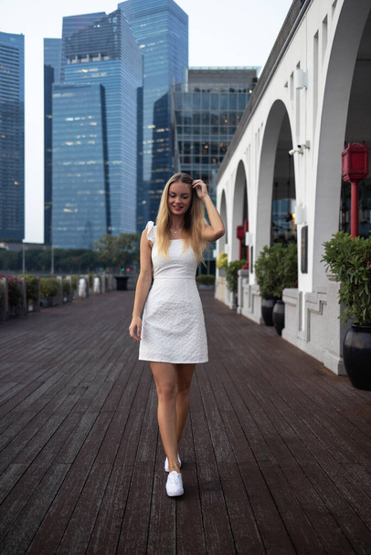 Young woman traveler with backpack and hat traveling into singapore city downtown. Travelling in Singapore concept. High quality photo - Photo, Image