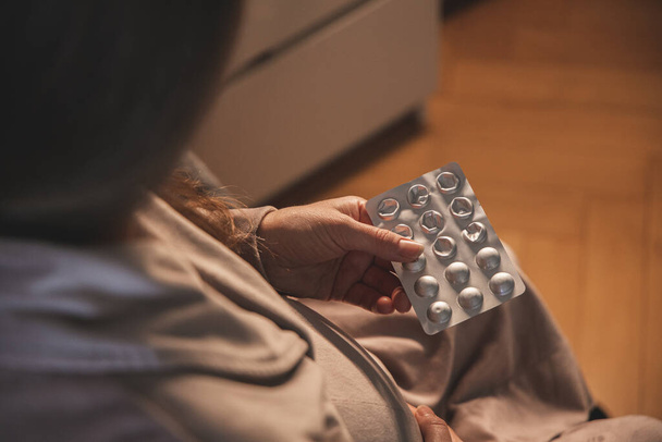 Вагітна молода жінка приймає таблетки або вітаміни. - Фото, зображення