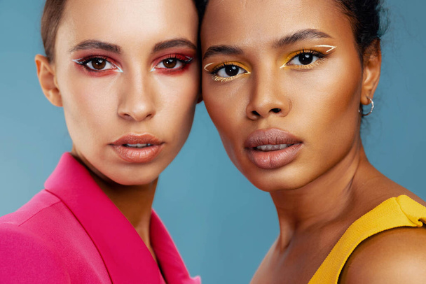 Frau Gesicht gemischt Porträt Haut zwei Körperpflege glücklich afrikanischen Studio Make-up Modell Schönheit bunt gelb amerikanisch attraktiv zusammen schöne Rasse Glanz - Foto, Bild