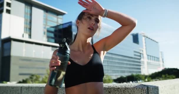 Exercise, tired or city woman drinking water, mineral liquid or beverage for wellness, hydration or refresh after cardio. H2O, thirsty or athlete fatigue sweat after outdoor training run for marathon. - Footage, Video