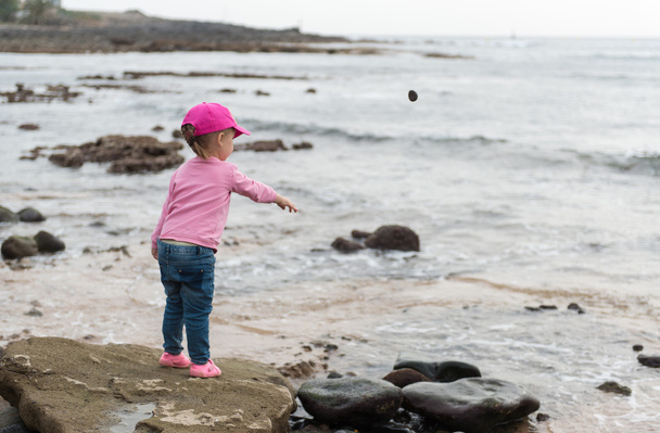 Little girl throwing stones into the sea - Fotografie, Obrázek