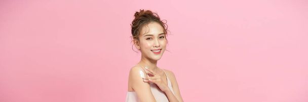 Gorgeous girl with soft makeup applying moisturizing skincare cream on shoulder - Фото, зображення