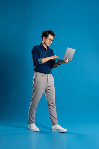 Портрет молодого азиатского бизнесмена, позирующего на синем фоне - Фото, изображение