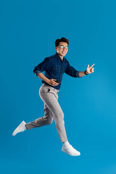 Retrato de un joven hombre de negocios asiático posando sobre fondo azul - Foto, imagen