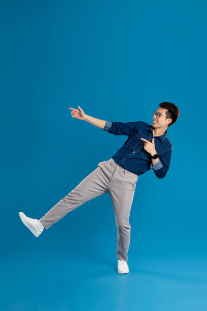 Retrato de un joven hombre de negocios asiático posando sobre fondo azul - Foto, imagen