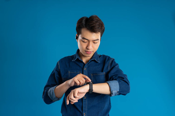 Muotokuva nuori aasialainen liikemies poseeraa sinisellä taustalla - Valokuva, kuva
