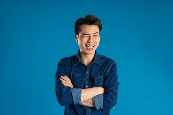 Retrato de un joven hombre de negocios asiático posando sobre fondo azul - Foto, Imagen