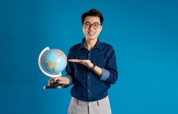 Porträt eines jungen asiatischen Geschäftsmannes, der auf blauem Hintergrund posiert - Foto, Bild