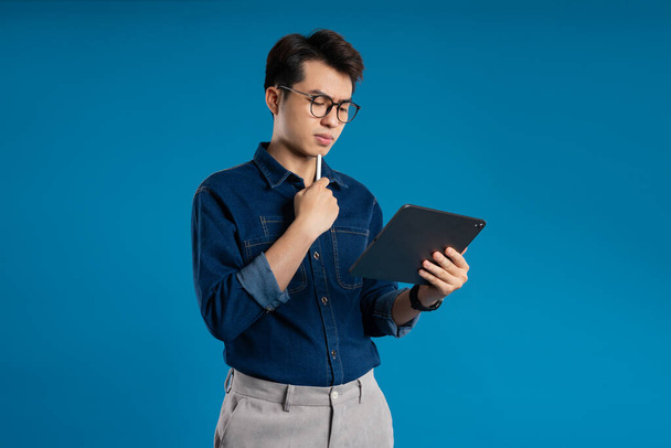 Portrait de jeune homme d'affaires asiatique posant sur fond bleu - Photo, image