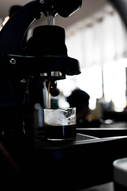Vertical shot of the Espresso machine making an espresso portafilter directs high-pressure hot water through the coffee puck. - Valokuva, kuva
