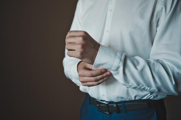 The young man dresses cuff links on a shirt 2291. - Фото, изображение