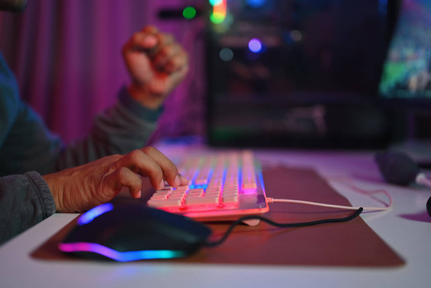 Großaufnahme männlicher Gamer, der auf der Gaming-Tastatur mit RGB-Licht tippt. Spiel-, Unterhaltungs- und Technologiekonzept - Foto, Bild