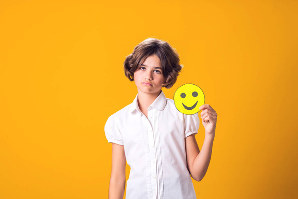 Расстроенная девушка держит счастливый смайлик. Концепция стресса и психологии - Фото, изображение