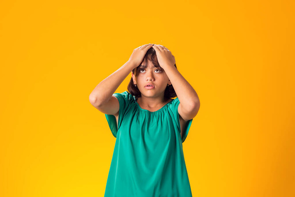 Smutna dziewczynka trzymająca głowę na żółtym tle. Koncepcja frustracji - Zdjęcie, obraz