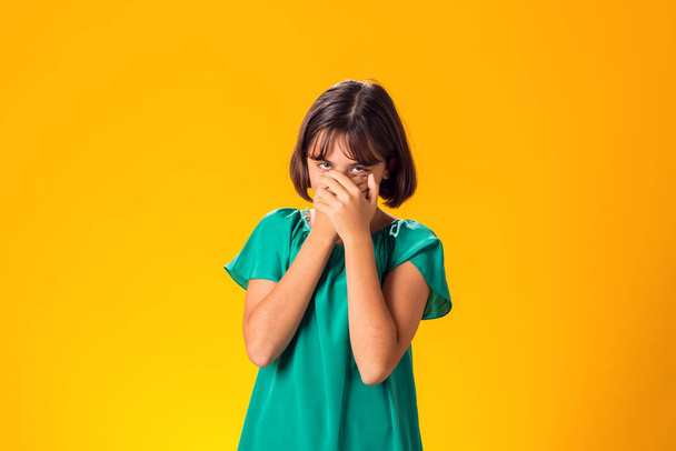 Angst Mädchen bedeckt Mund mit Händen über gelbem Hintergrund - Foto, Bild