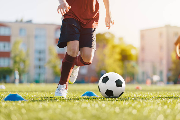 Jugador de fútbol en el campo con pelota. Primer plano de un chico pateando una pelota de fútbol. Taladro Slalom durante una sesión de entrenamiento de fútbol - Foto, Imagen