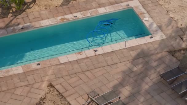 Service und Wartung des Schwimmbades in einem Hotel an sonnigen Tagen. Reinigungsschlauch in einem Pool zurückgelassen - Filmmaterial, Video