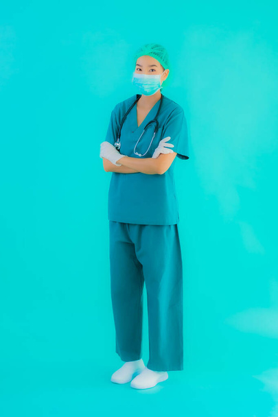 Porträt schöne junge asiatische Ärztin mit Maske und Brille zum Schutz vor Covid19 oder Coronavirus auf blauem Hintergrund - Foto, Bild