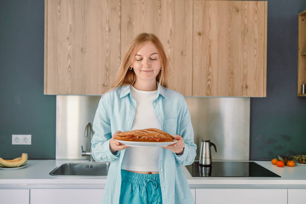 Aufnahme einer hungrigen jungen Frau, die ein gesundes Sandwich isst und morgens zu Hause in der Küche frühstückt - Foto, Bild