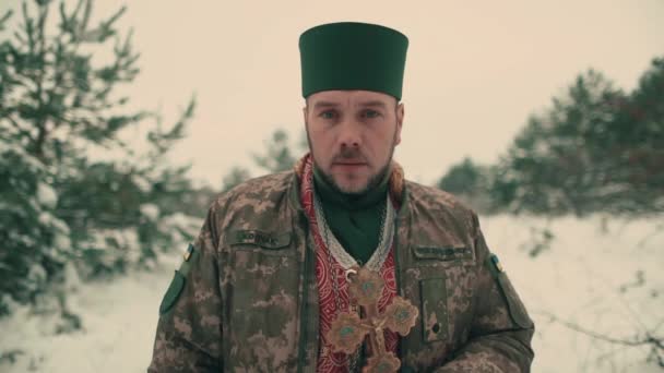 Ukrayna ordusunun askeri üniformalı papazı. Karlı bir alanda genç bir papazın portresi. Ukrayna 'nın Rusya ile savaşı. - Video, Çekim