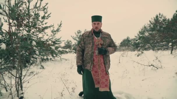 Ukrayna ordusunun askeri üniformalı papazı. Karlı bir alanda genç bir papazın portresi. Ukrayna 'nın Rusya ile savaşı. - Video, Çekim