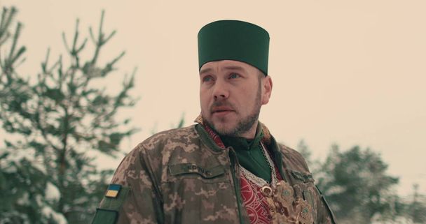 Capellán en uniforme militar del ejército ucraniano. Retrato de un joven capellán en un espacio cubierto de nieve. La guerra de Ucrania con Rusia. - Foto, Imagen