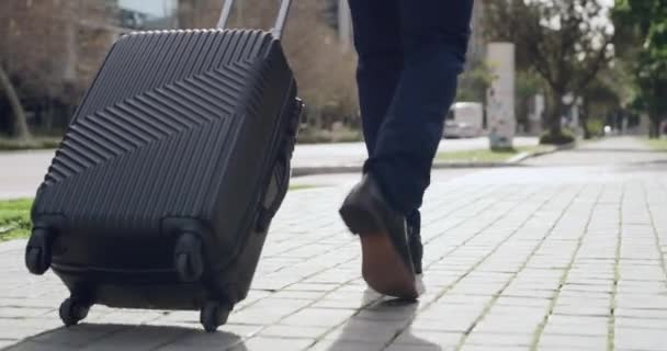 Homme d'affaires avec valise ou bagage, marchant jusqu'à destination lors d'un voyage d'affaires dans une rue urbaine moderne. jambes à angle bas d'un homme formel professionnel avec bagages de voyage arrivant à l'étranger. - Séquence, vidéo